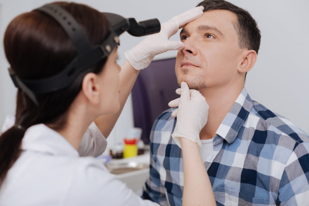 Doctor looking at male patients nose after rhinopolasty