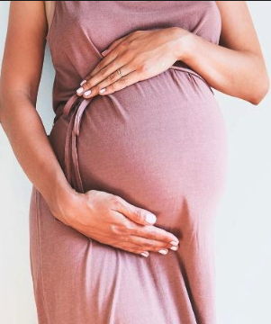 Woman holding her hands over pregnant stomach