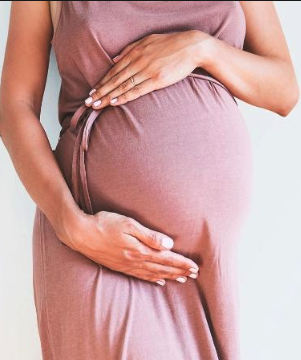 Mommy Makeover Dallas Woman holding her hands over pregnant stomach
