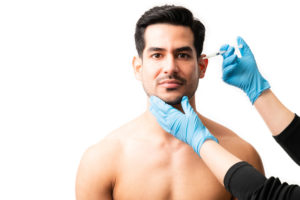 Closeup of doctor's hands injecting botox into the skin of male model on white background