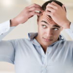 Man checking hairline, in a bathroom