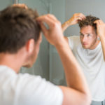 man checking his hair in the bathroom mirror