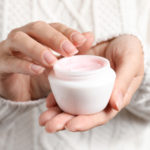 Woman holding jar of moisturizing cream, closeup