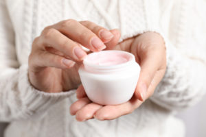 Woman holding jar of moisturizing cream, closeup