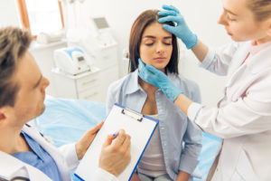 two doctors are examining her face and making notes