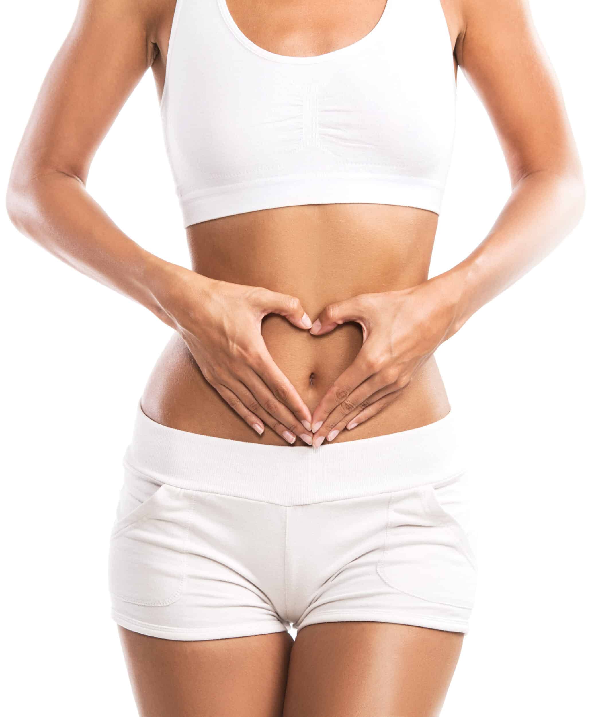 Fit young woman holding a heart over her abdomen, isolated on white background