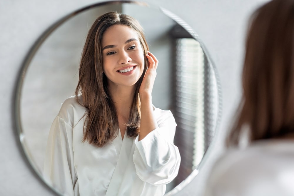 A woman looking in the mirror after Sculptra® in Lewisville